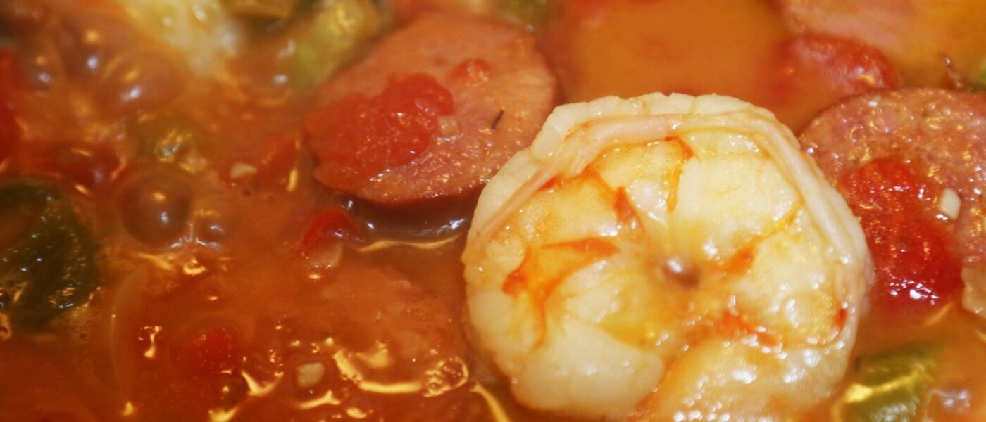 Chicken, andouille, and shrimp gumbo simmering in a dark roux with peppers and tomatoes