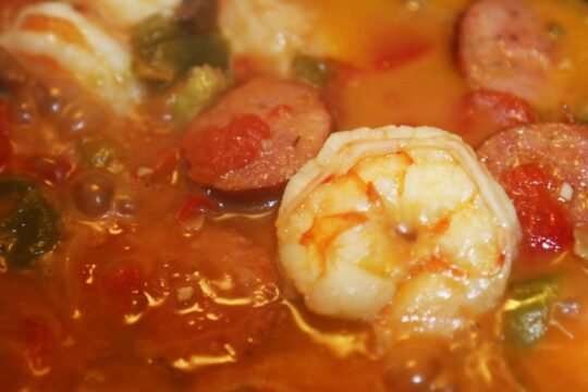 Chicken, andouille, and shrimp gumbo simmering in a dark roux with peppers and tomatoes