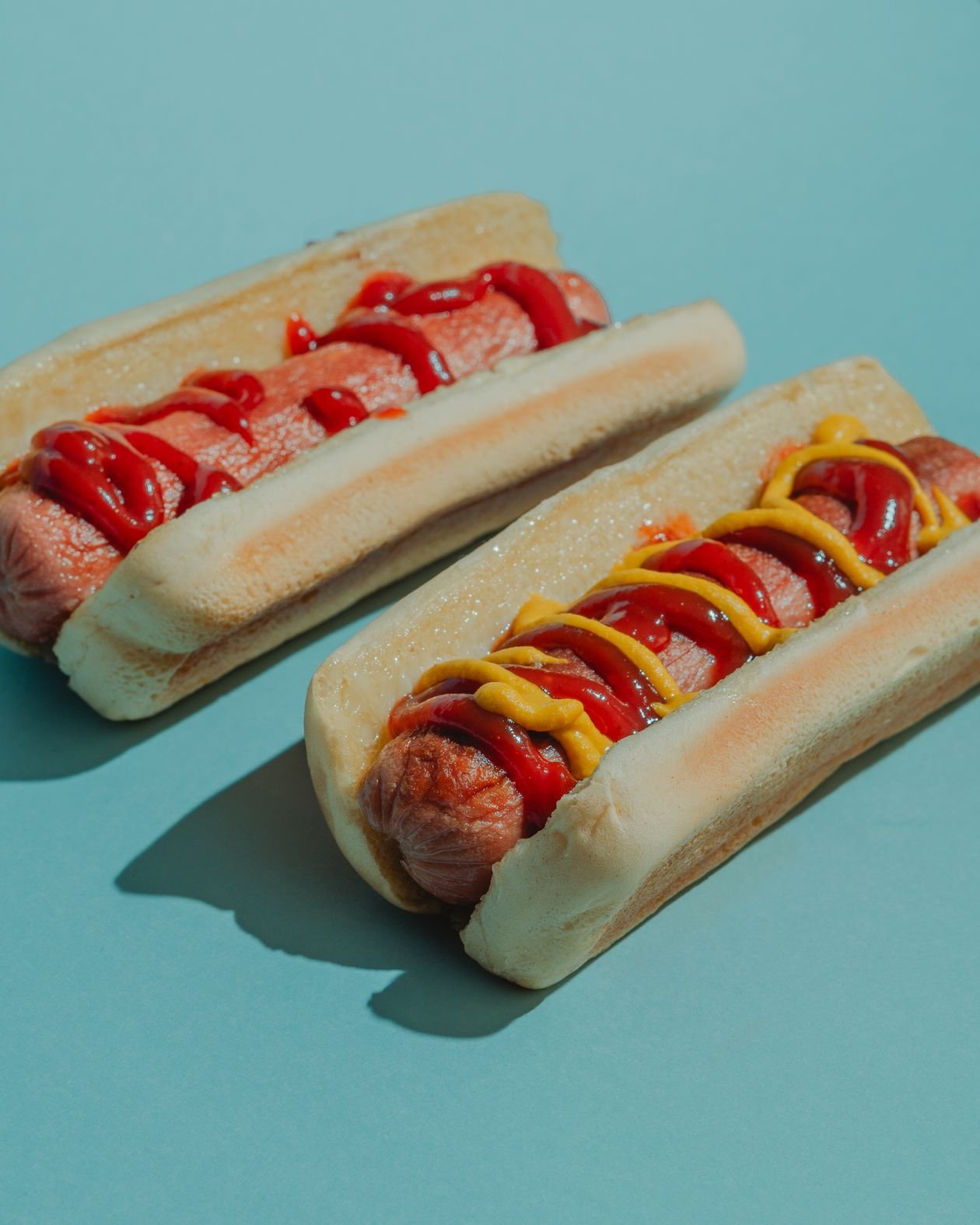 Grilled hot dogs in buns with ketchup and yellow mustard