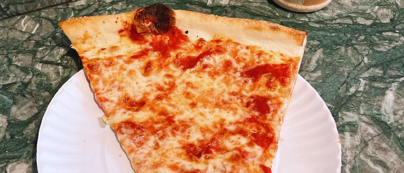 Classic New York-style cheese pizza slice on a paper plate