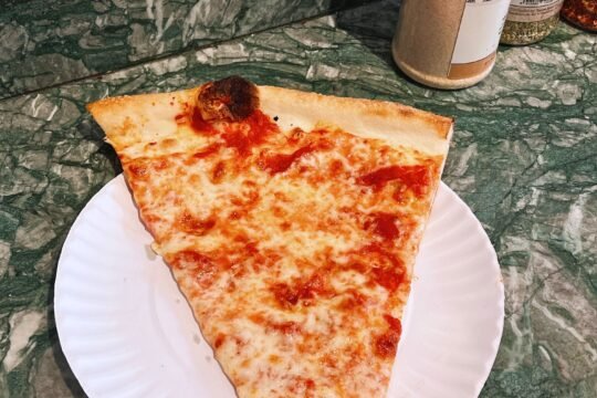 Classic New York-style cheese pizza slice on a paper plate