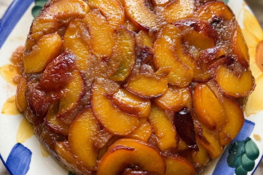 Cast iron peach upside-down cake just flipped out of the skillet, caramelized peach slices arranged over a golden vanilla cake