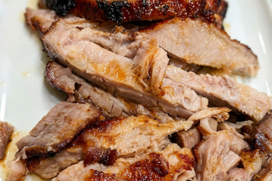 Sliced oven-roasted pork belly with a dark caramelized brown sugar and smoked paprika crust, arranged on a plate