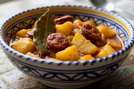 A rustic bowl of Patatas a la Riojana, torn potatoes and sliced chorizo in a thick paprika-red broth