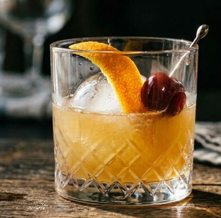 Whiskey Sour in a rocks glass over ice, garnished with an orange peel twist