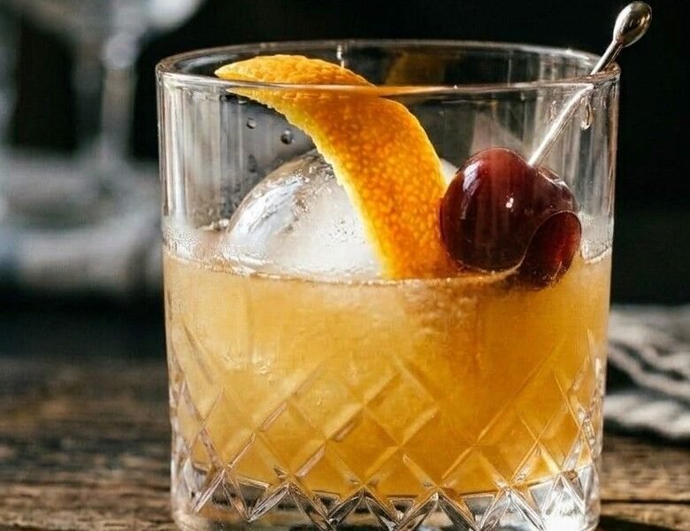 Whiskey Sour in a rocks glass over ice, garnished with an orange peel twist