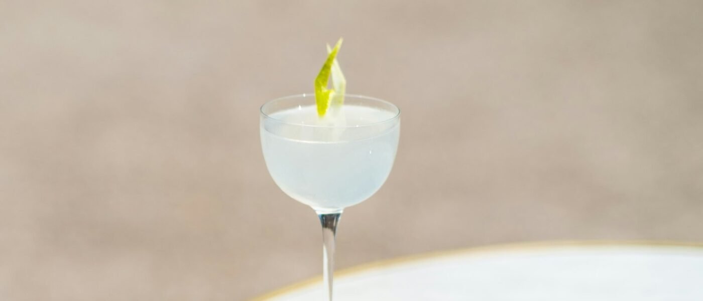 A pale, chilled Daiquiri in a coupe glass garnished with a lime twist on a marble table